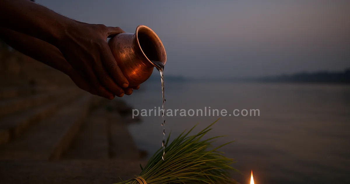 Hands pouring water with black sesame onto darbha grass by a river at dawn beside an oil lamp — amavasya significance | pariharaonline.com