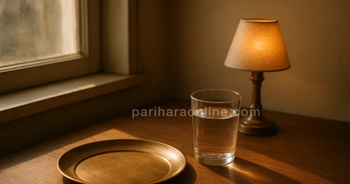 Empty brass plate and a glass of water beside a small lamp and a book on a sunny table — fasting and focus | pariharaonline.com