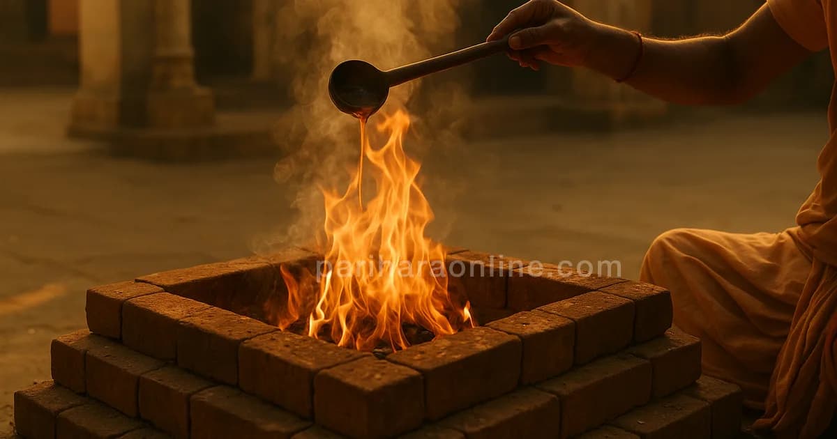 Hand pouring ghee from a wooden ladle into a homam fire in a temple courtyard — what is a homam | pariharaonline.com